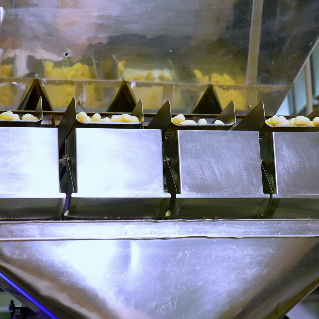 Metal automated equipment at food factory. Modern process of snack production. Yellow corn sticks in factory machine