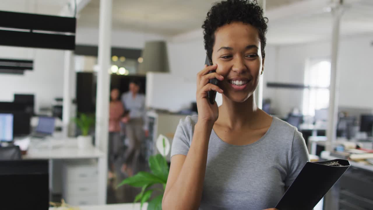 Happy biracial businesswoman making call in office