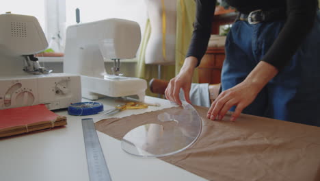 dressmaker using chalk and french curve ruler for marking fabric