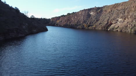 Deep-blue-lake-forms-in-flooded-ancient-tin-mine-near-Golpejas,-Spain