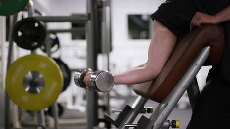 Un-Hombre-Haciendo-Flexiones-De-Bíceps-Con-Mancuernas-En-Un-Banco-De-Predicador-Con-Un-Peso-Ligero-Usando-El-Brazo-Derecho