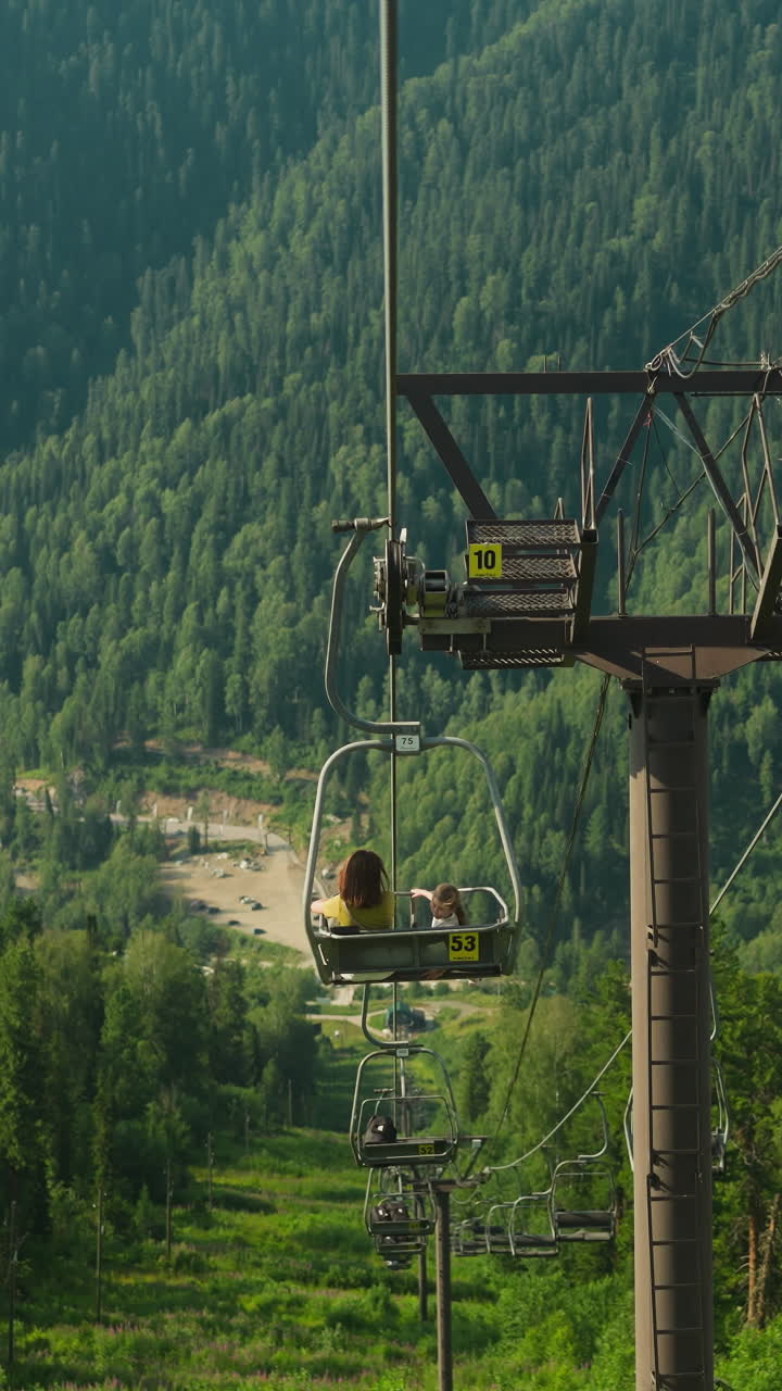 Descent from viewing platform with green grass visible from cable car. Tourists delight in contemplating amazing view of extensive forest and mountains