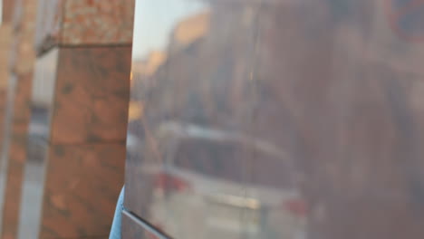 Close-up-view-of-blonde-young-woman-coming-out-of-the-column-on-the-street-and-taking-a-photo-with-a-camera