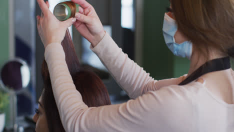 Eine-Friseurin-Mit-Gesichtsmaske-Legt-Lockenwickler-In-Das-Haar-Einer-Kundin-Im-Friseursalon