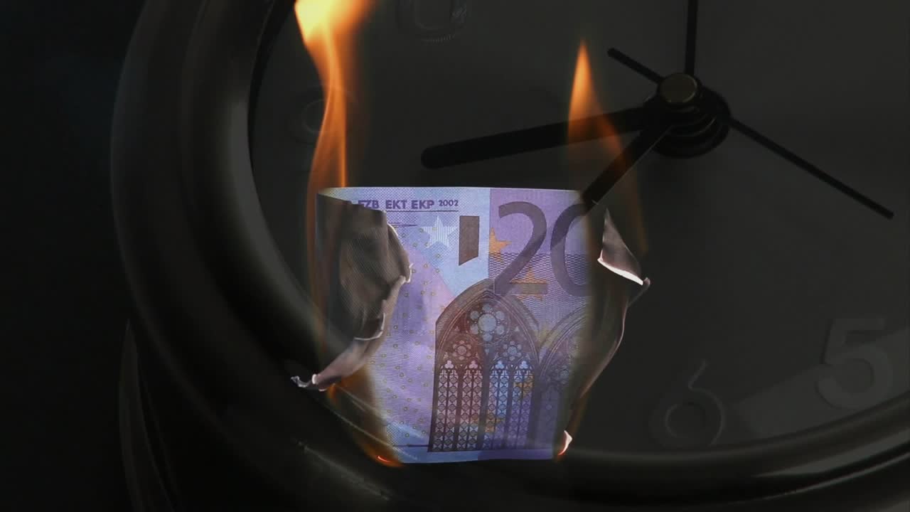 En 20 euroseddel antændes i kanterne, brænder og smuldrer til faldende aske, hvilket viser hvordan tiden ødelægger penge.