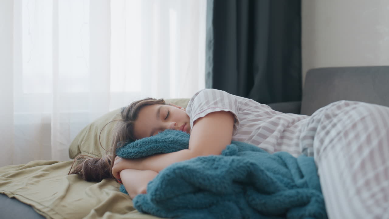 Caucasian Remote Worker Napping On Sofa, Striped Pajamas Suggest Weekend Reset, Blue Throw Blanket, Soft Window Light, Candid Closeup, Stress Relief, WorkLife Balance Moment, Slow Breath And Pause