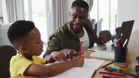 Afroamerikanischer-Vater-Und-Sohn-Machen-Hausaufgaben-Und-Benutzen-Gemeinsam-Einen-Laptop