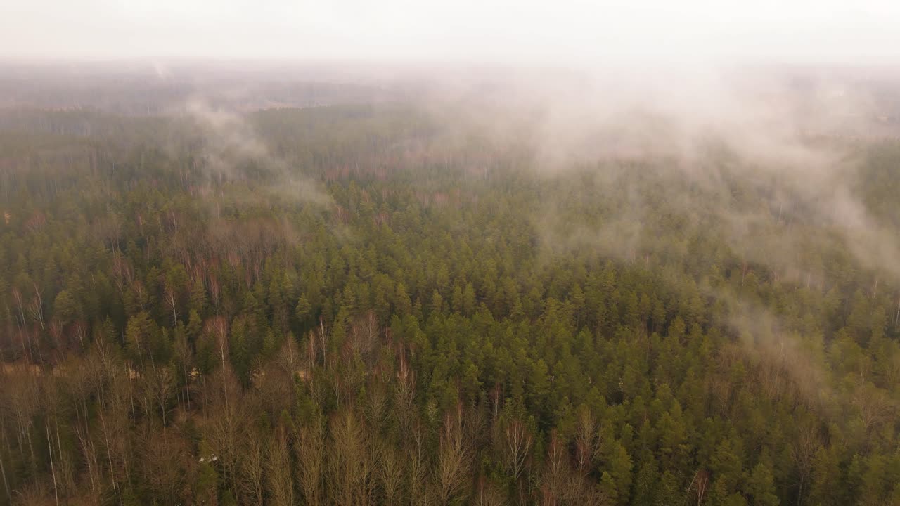 Aerial view of a winding river through autumn fields and forests under an overcast sky, with visible power lines crossing the open land.