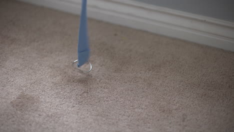 static shot of a baby blue yoga strap being laid down onto a carpeted floor