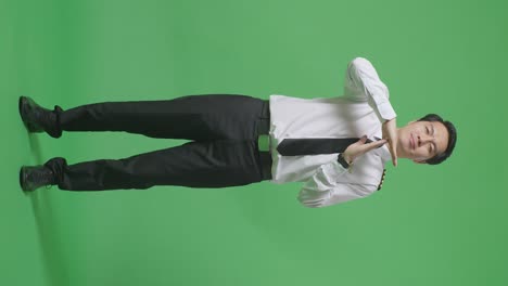 full body of asian man pilot looking at camera and showing time out hands gesture while standing in the green screen background studio