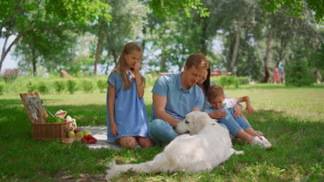 familia feliz uso de la tableta en un picnic. padres viendo computadora portátil con dos niños fuera