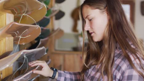 video of caucasian female skateboarder searching for skateboard in skate shop