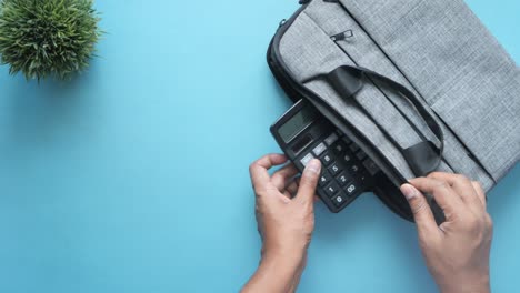 man opening a grey laptop bag on blue table