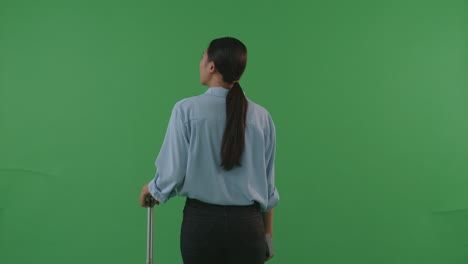 vista trasera mujer asiática viajera con equipaje caminando y de pie en el estudio de fondo de pantalla verde, durante la hora de la puesta del sol