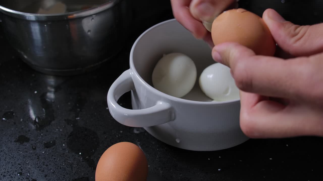 pelar a mano el huevo orgánico duramente hervido en la cocina