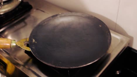 close-up of dosa batter spreading on hot tawa in home kitchen. traditional indian breakfast cooking on stove