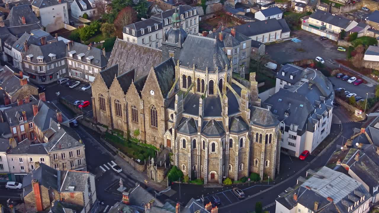 Kallistettu panoraama-drone lentää lähellä goottilaistyylistä ja historiallista Basilique Notre-Dame-des-Miracles -kirkkoa Mayennessa, Ranskassa.