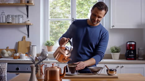 man making pour-over coffee in a kitchen