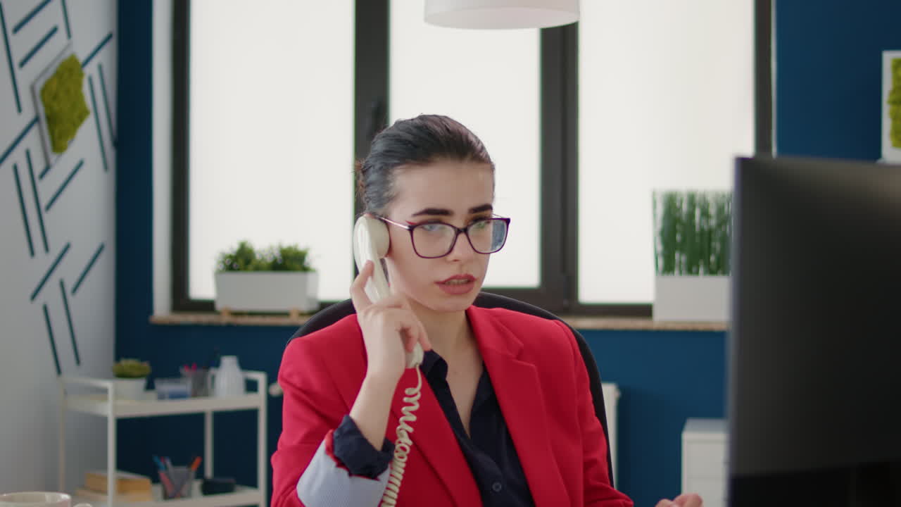 Asistente financiero usando un teléfono fijo para responder a una llamada remota