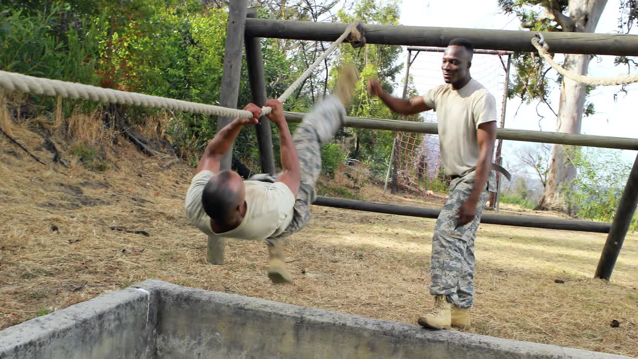 Military soldier climbing rope during obstacle course