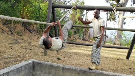 military soldier climbing rope during obstacle course