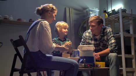 Parents and boy work with pottery wheel in the workshop