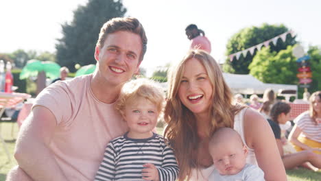 slow motion portrait of family with children sitting on grass at summer garden fete