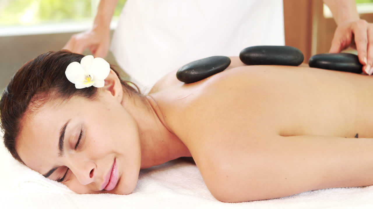 una mujer joven recibiendo un masaje de piedras calientes.