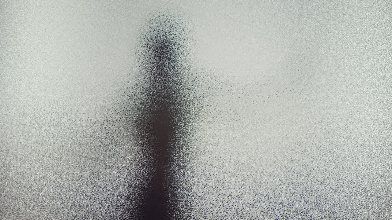 A female silhouette behind the frosted window dances slowly