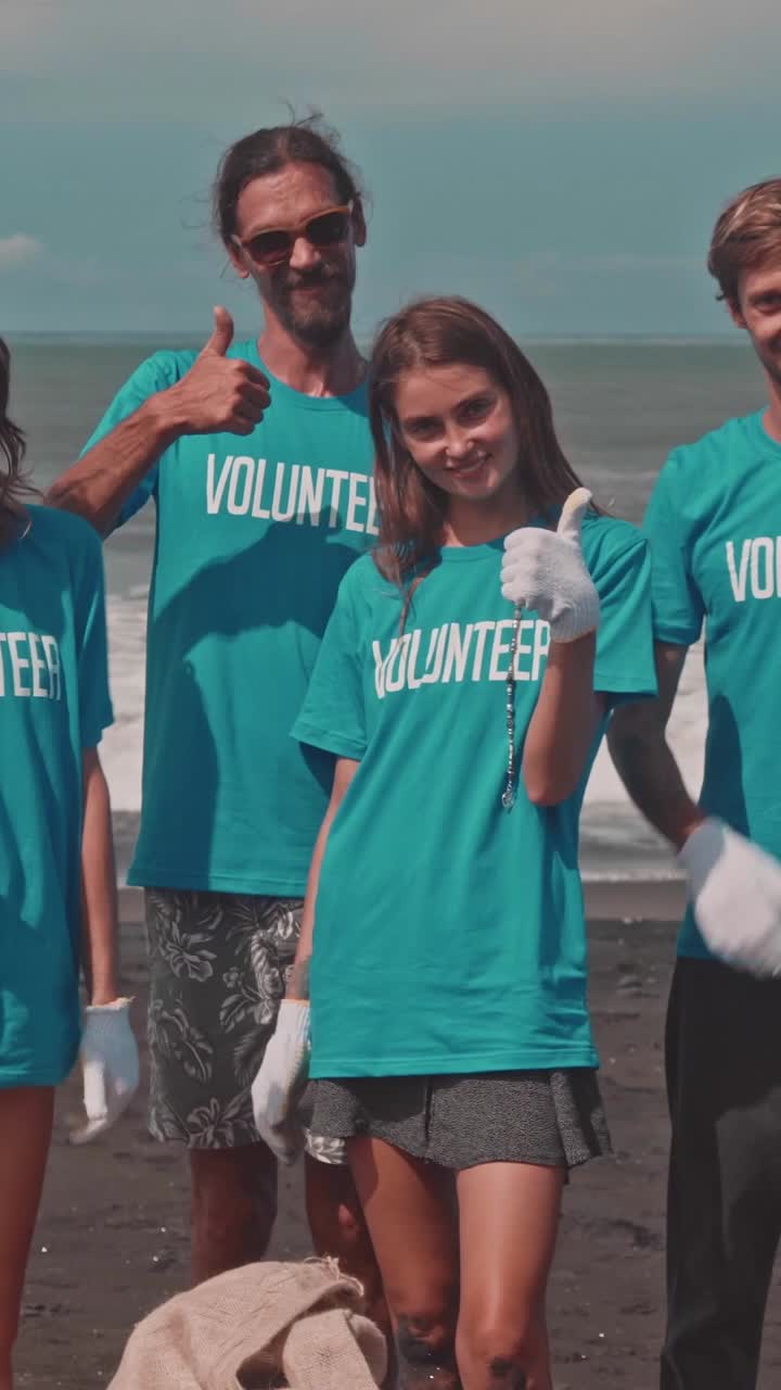 Caucasian eco activists showing thumbs up after cleaning beach from garbage