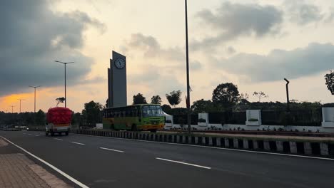 Monumento-Con-Reloj-En-La-Avenida-Asiática-Durante-La-Puesta-De-Sol,-Lanzadera-Pasando,-India