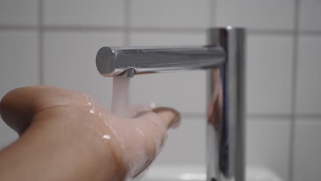 close-up of hand washing under a motion sensor faucet