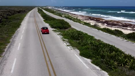 Vista-Aérea-De-Un-Coche-Rojo-Conduciendo-Por-Una-Carretera-De-Playa-En-Cozumel