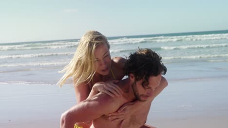 man giving piggyback ride to woman at beach