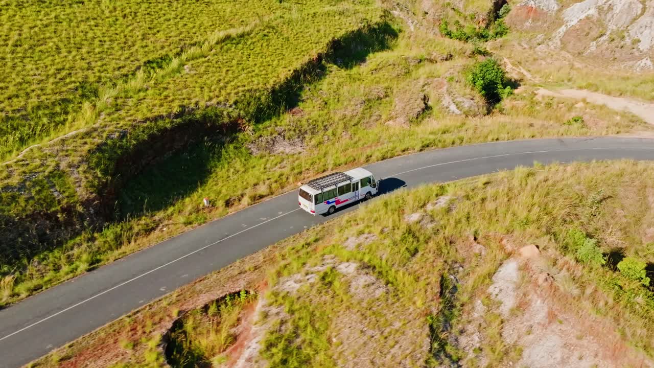 Scenic aerial view of a local bus navigating a winding road through Madagascar’s highland terrain. Captured from above, the video highlights rural transportation and natural surroundings.