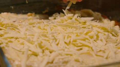 sprinkling grated cheese on a baking dish