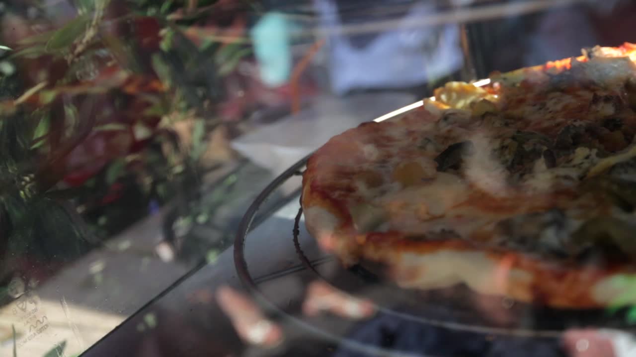 Freshly cooked pizza spinning in a display cabinet at a street food market.