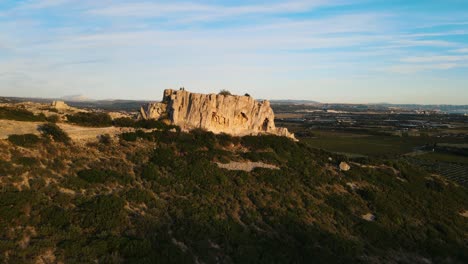 Aerial-orbiting-shot-of-a-rock-formation-surrounded-by-vineyards-in-France