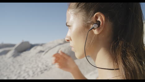 fitness, auriculares y mujer comienzan en una playa