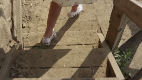 Woman-running-down-wooden-stairs-to-beach-close-up.-Slim-girl-legs-in-sneakers.
