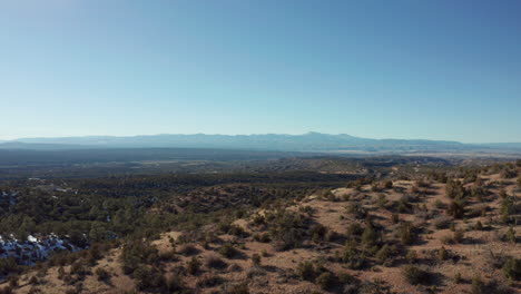 aerial moving sideways through desert hills with scrub bushes and light snow