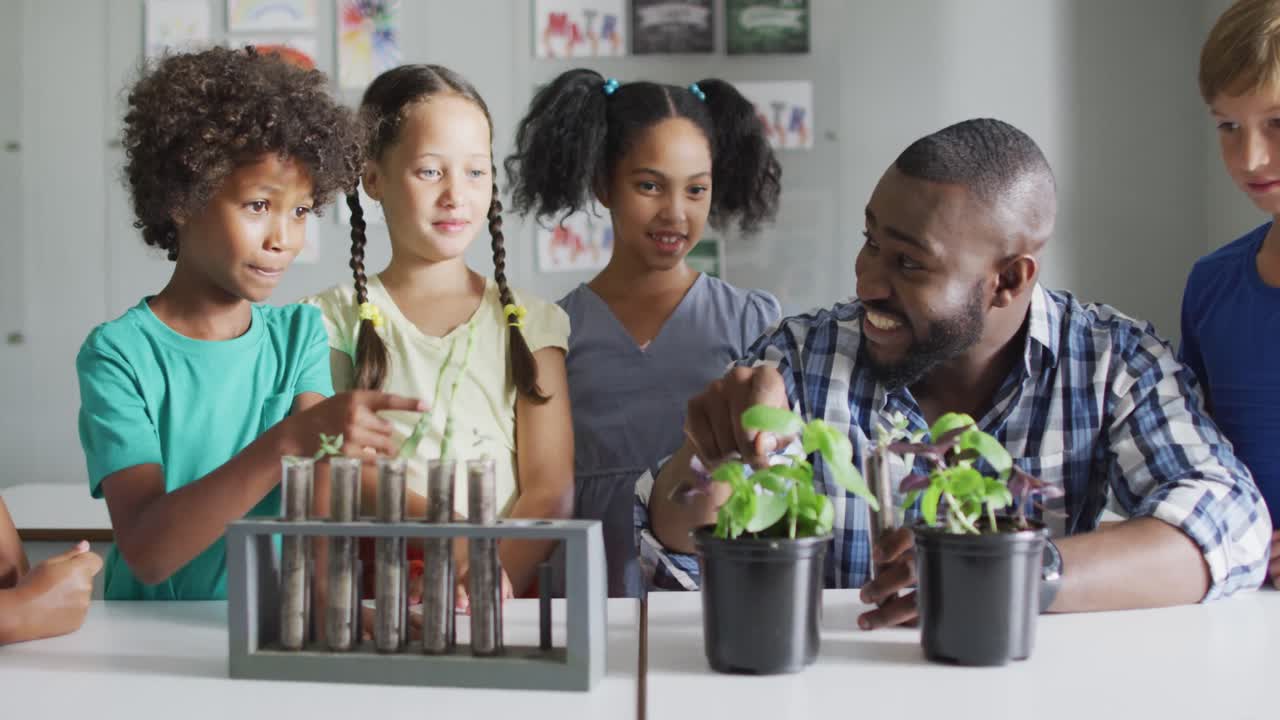Video of happy african american male teacher and class of diverse pupils during biology lesson