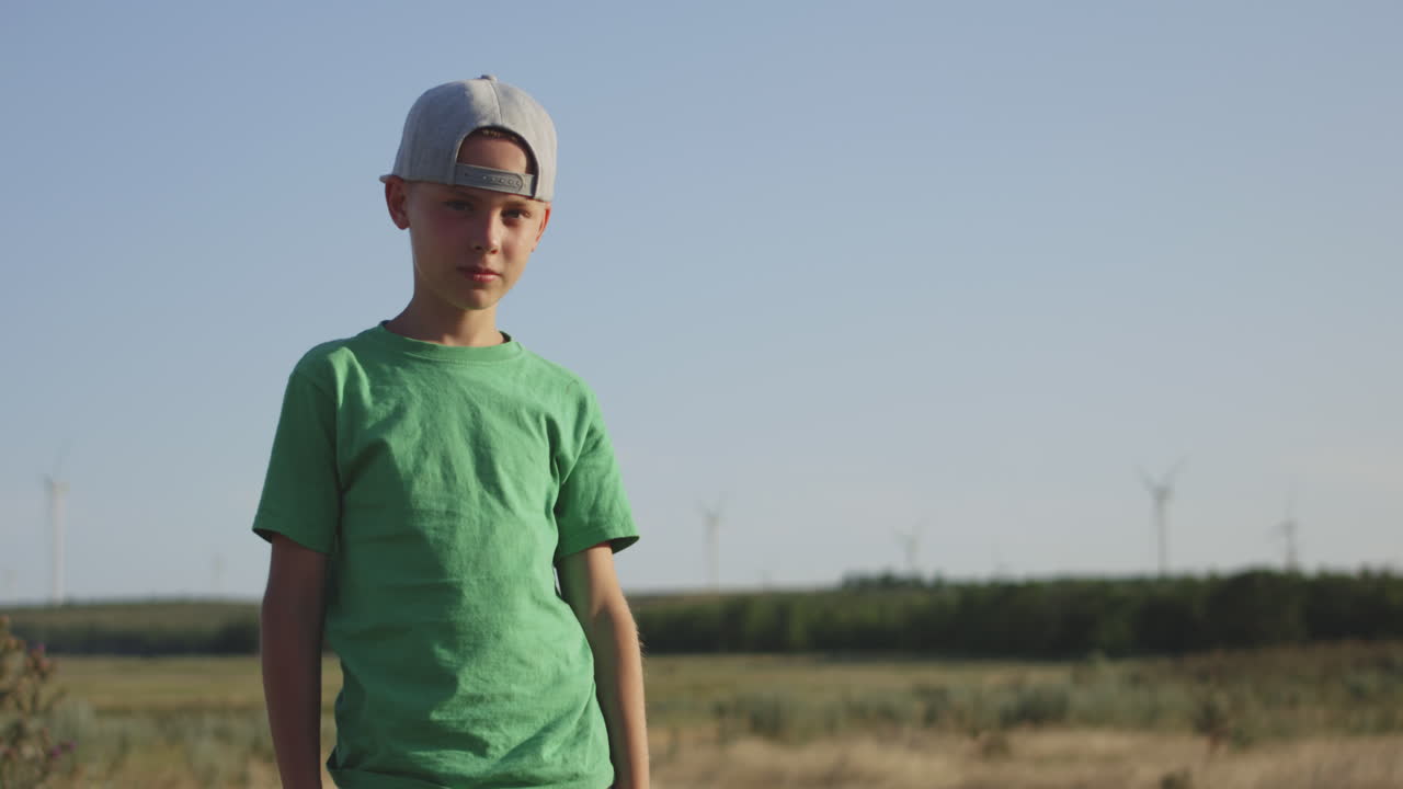 Portrait of a boy in a field with wind turbines