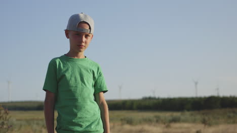 portrait of a boy in a field with wind turbines