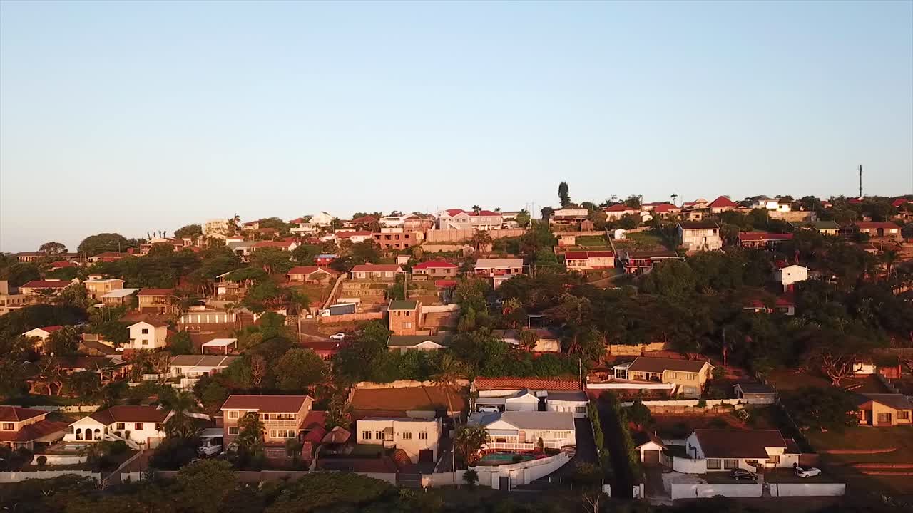 dron volando sobre algunas coloridas casas residenciales con una ligera vista del mar en la distancia en el acantilado en durban, sudáfrica