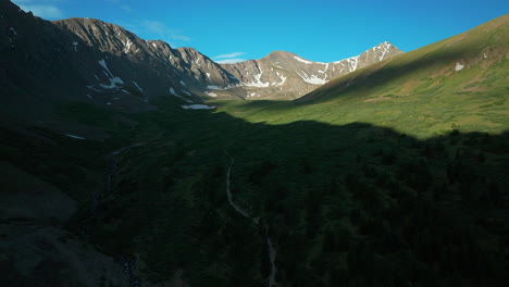 Aerial-cinematic-drone-early-morning-sunrise-trailhead-Grays-and-Torreys-14er-Peaks-Rocky-Mountains-Colorado-stunning-landscape-view-mid-summer-green-beautiful-snow-on-top-forward-pan-up-movement