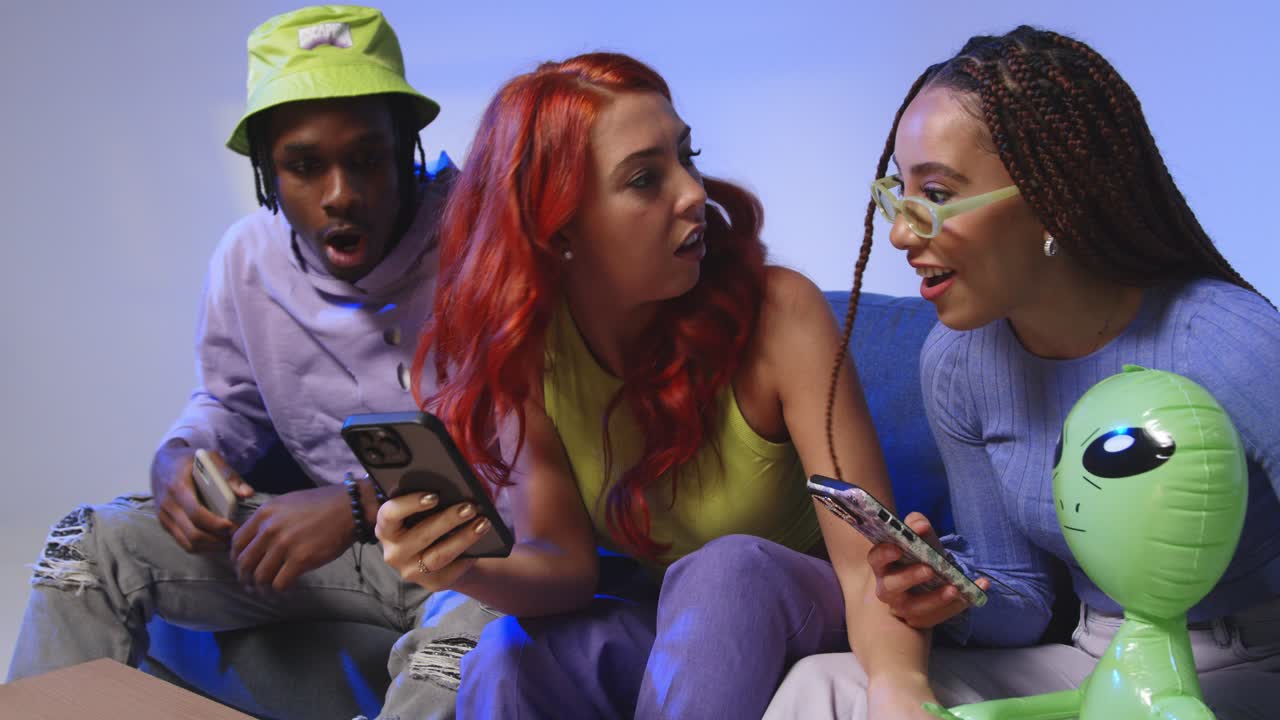 fotografía de estudio de amigos jóvenes de la generación z sentados en el sofá compartiendo publicaciones en las redes sociales en teléfonos móviles