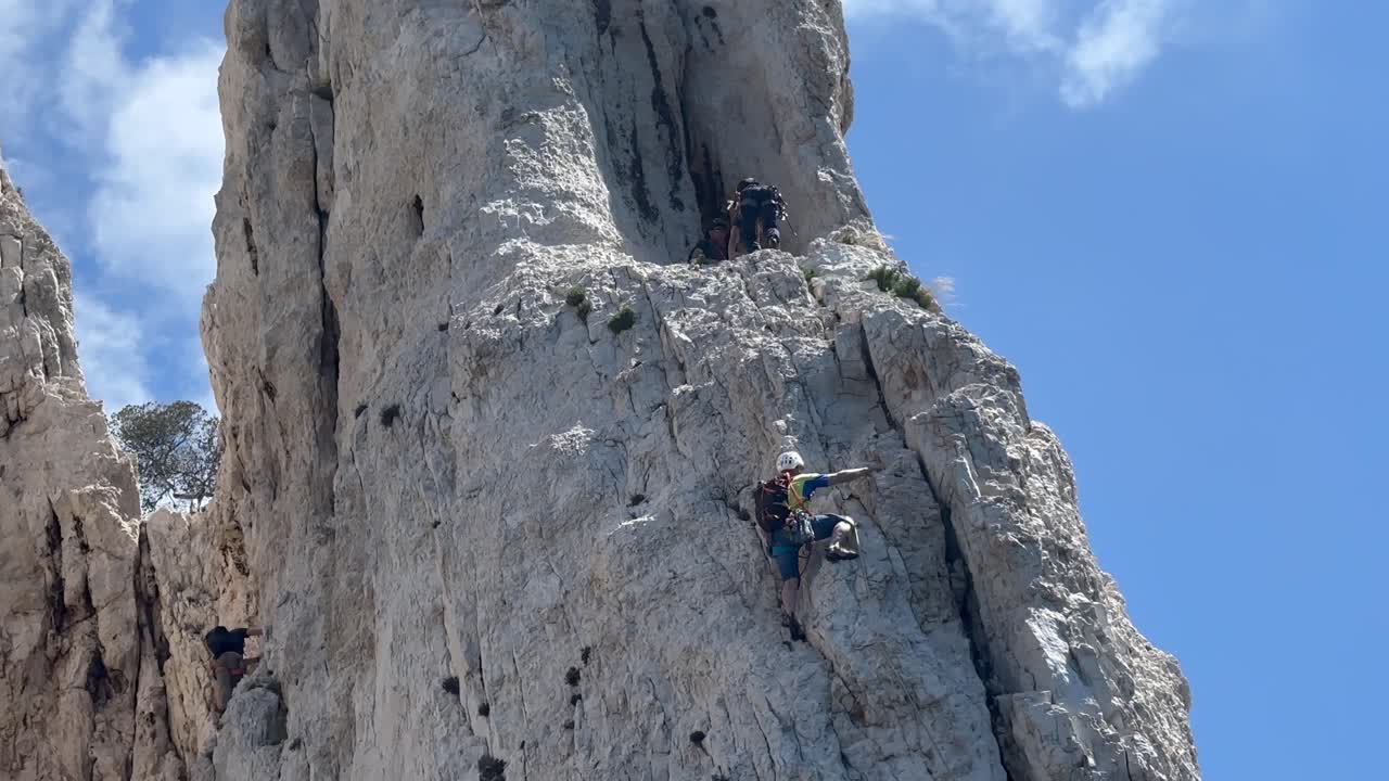 Dangerous scene of professional mountain climber on steep cliff in France. Sunny day with blue sky. View from boat bottom up. Extreme sport.