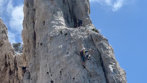 dangerous scene of professional mountain climber on steep cliff in france. sunny day with blue sky. view from boat bottom up. extreme sport.