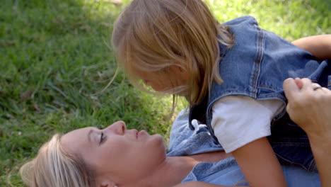 Young-daughter-lying-on-her-mother-in-a-park,-elevated-view